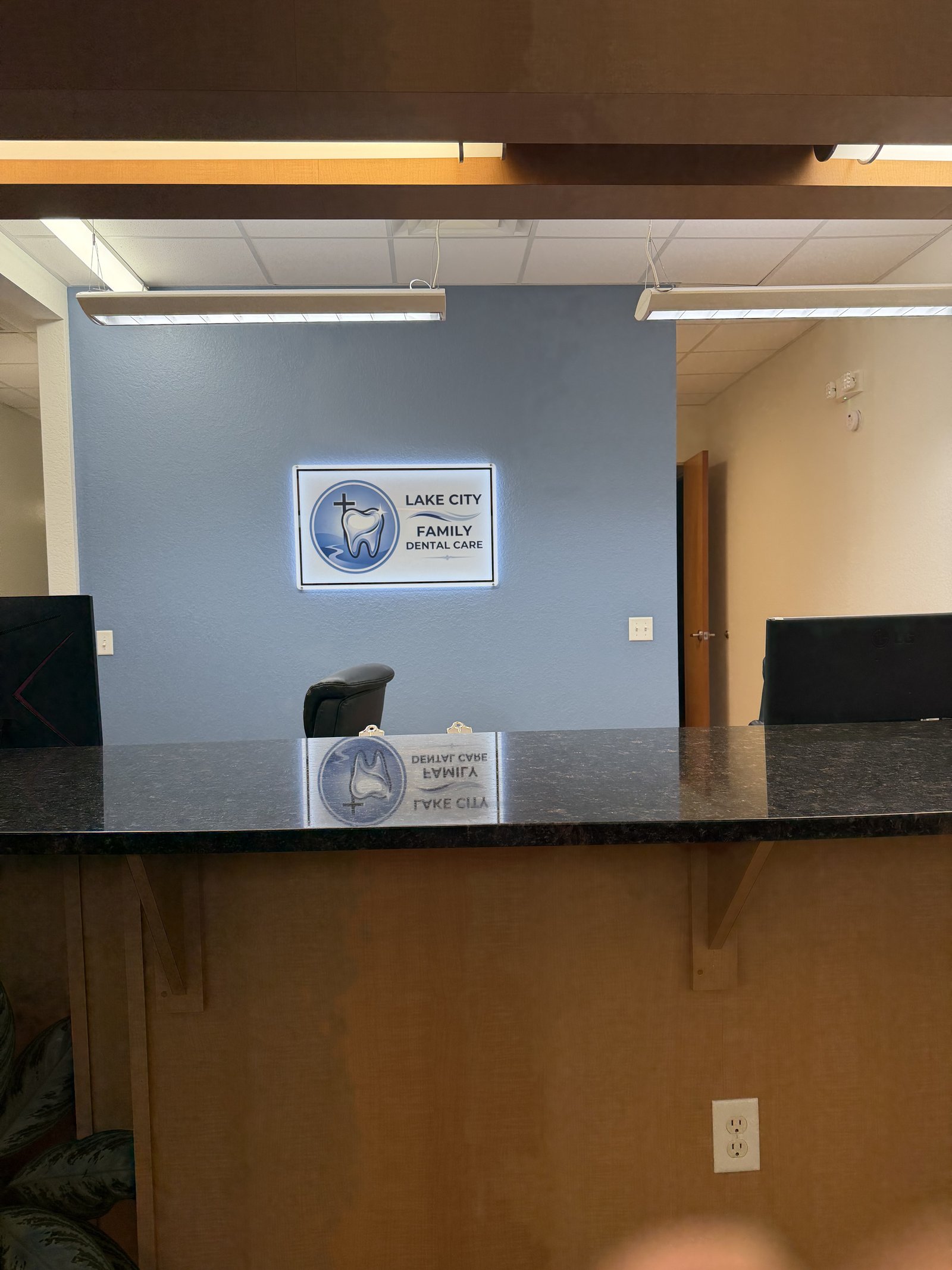 Illuminated Lake City Family Dental Care logo on blue accent wall
