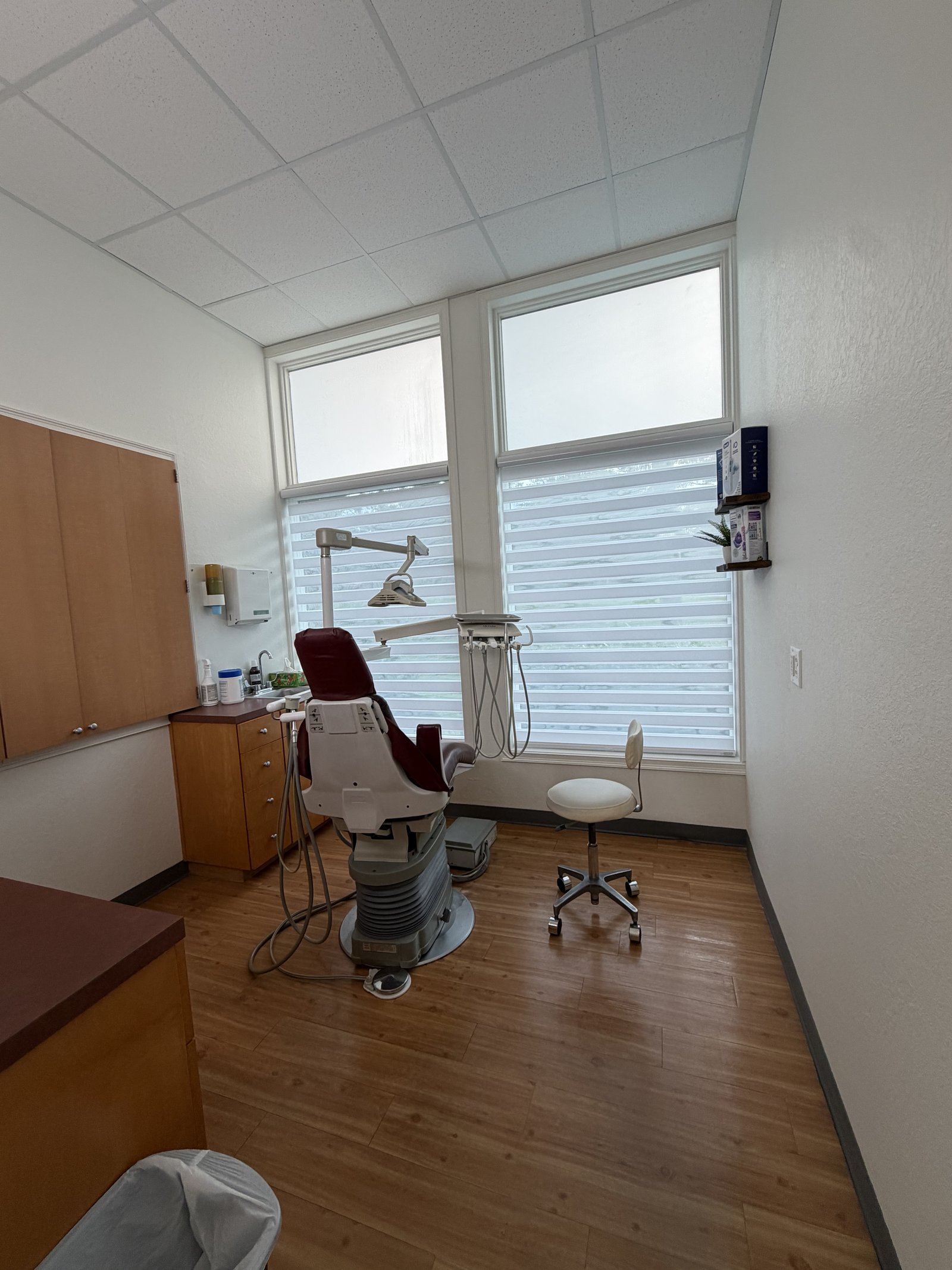 Bright treatment room with dental chair and windows